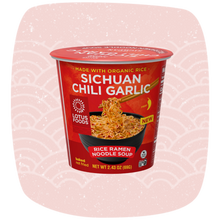 Load image into Gallery viewer, A cup of Lotus Foods Sichuan Chili Garlic Rice Ramen Noodle Soup, shown in its red packaging against a light pink background with a subtle wave pattern.
