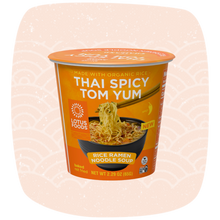 Load image into Gallery viewer, A cup of Lotus Foods Thai Spicy Tom Yum rice ramen noodle soup, shown in its orange and white packaging against a light peach background with a faint wave pattern.
