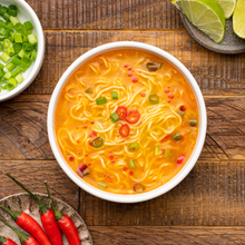 Load image into Gallery viewer, Overhead shot of a white ceramic bowl of Lotus Foods Thai Spicy Tom Yum Rice Ramen Noodle Soup, on a dark wooden backdrop.
