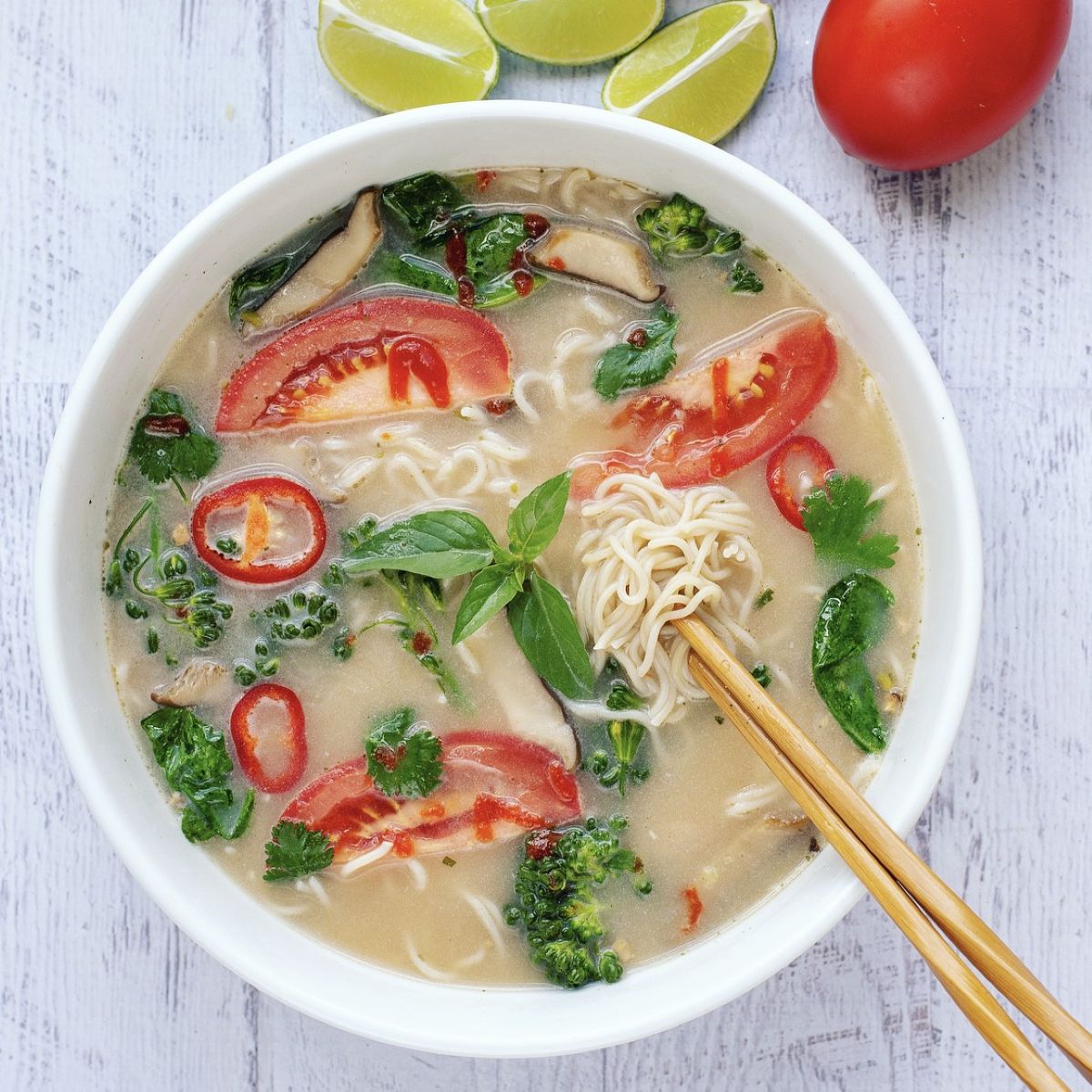 Bowl of noodle soup with vegetables on a white background