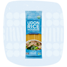 Load image into Gallery viewer, A package of Lotus Foods Brown &amp; White Udon Rice Noodles, featuring a blue bag with a photo of prepared noodles on the front, set against a light blue patterned background.
